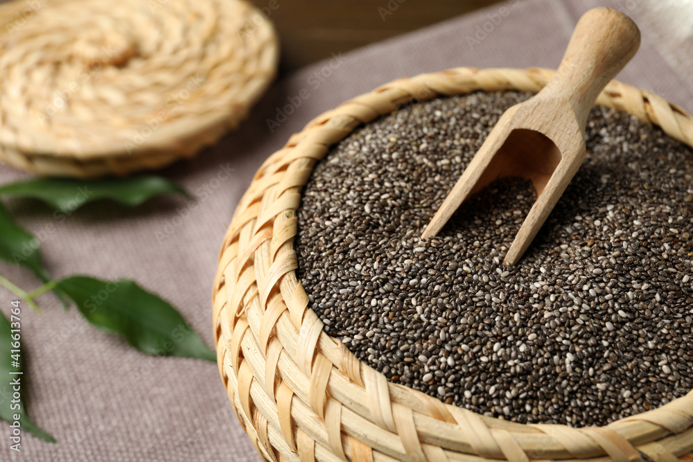 Wicker box with chia seeds and scoop on table, closeup
