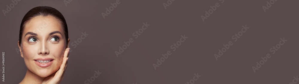 Young cute female face on brown banner background with copy space. Healthy model woman smiling and looking up Young cute female face on brown banner background with copy space. Healthy model woman smiling and looking up