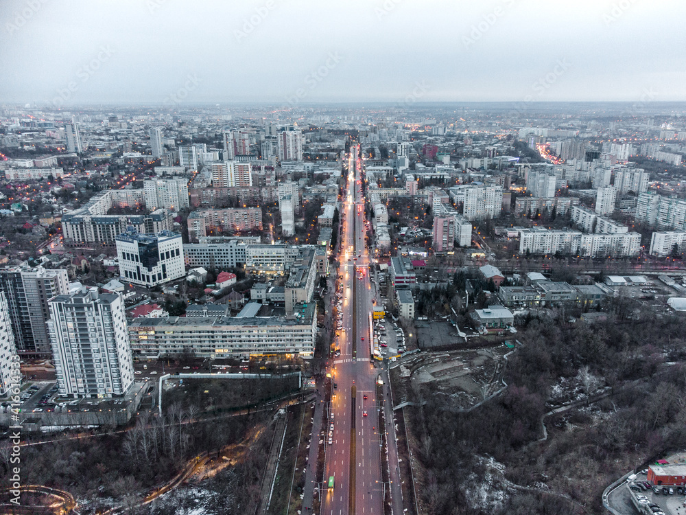 Aerial view Kharkiv city center Nauky avenue. Botanical garden Sarzhyn Yar and multistorey modern high buildings in evening. Grey winter city with red street lights