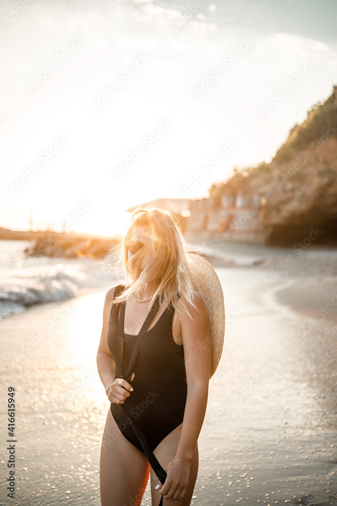 young woman in a swimsuit with a beautiful figure on the seashore at sunset. Selective focus young woman in a swimsuit with a beautiful figure on the seashore at sunset. Selective focus