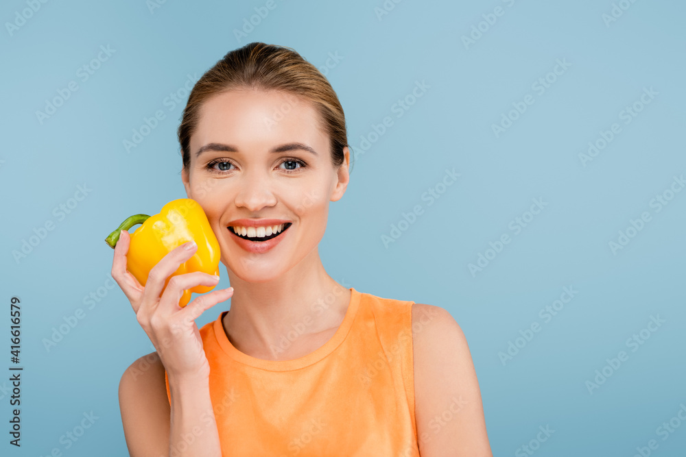 charming woman with natural makeup holding bell pepper isolated on blue charming woman with natural makeup holding bell pepper isolated on blue