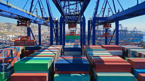 Aerial closeup photo of colourful container seaside port and logistics terminal in crane area while loading-unloading to container tanker vessel photo