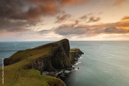 Neist Point and the lighthouse on Isle of Skye at sunset with beautiful colourful clouds in background - Scotland, UK.