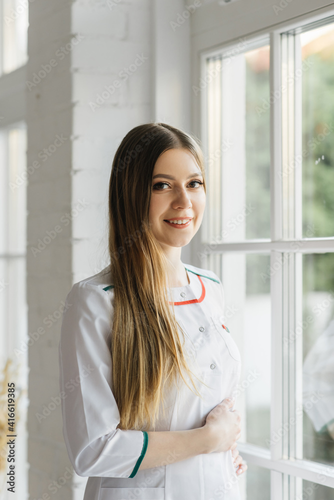 Attractive young girl in a white medical gown in a beautiful interior, VIP clinic, beauty and relaxation salon