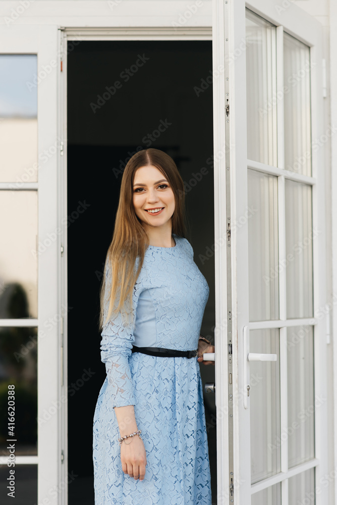 Attractive young girl on the background of the white house in a blue dress Attractive young girl on the background of the white house in a blue dress