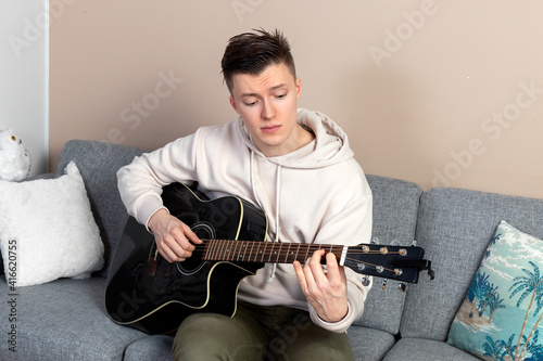 Young man plays guitar at home. Musical hobby. Leisure during quarantine.