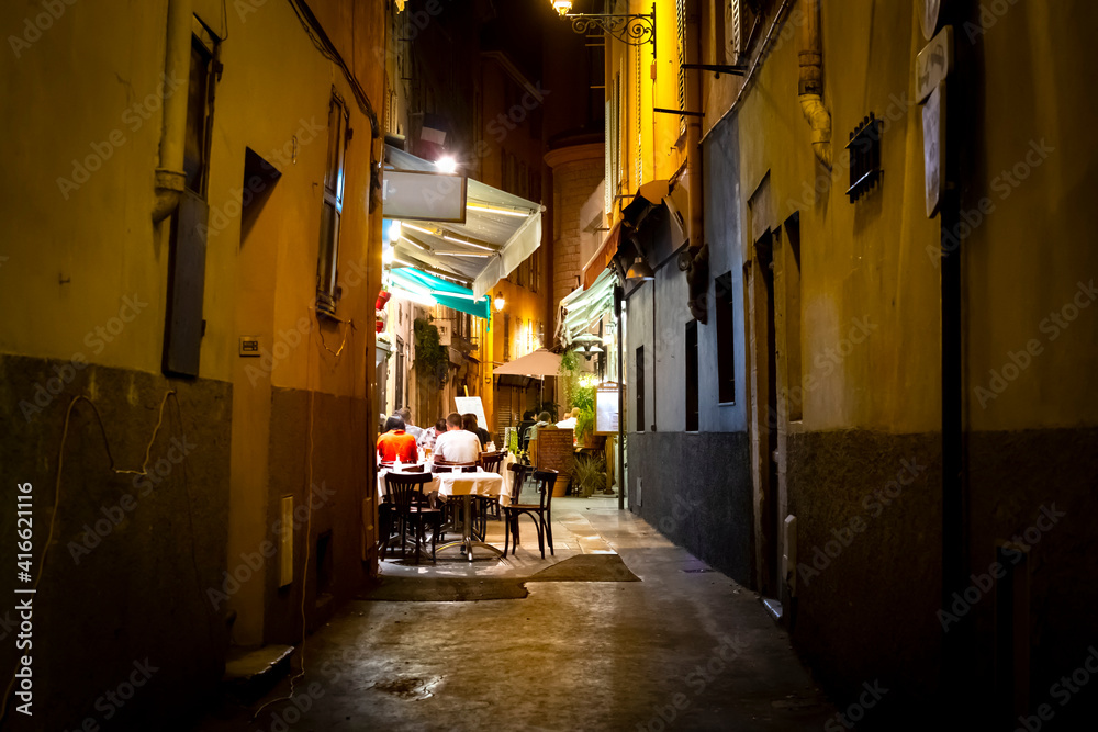 Tourists enjoy a late dinner at a cafe in a narrow alley in the Vieux Nice Old Town of Nice, France, on the French Riviera.
