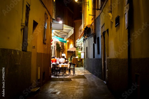 Fototapeta Naklejka Na Ścianę i Meble -  Tourists enjoy a late dinner at a cafe in a narrow alley in the Vieux Nice Old Town of Nice, France, on the French Riviera.