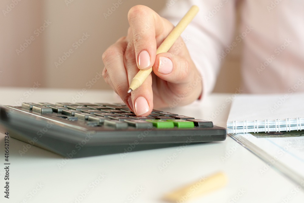 close up of woman hand with calculator counting and taking notes to notebook close up of woman hand with calculator counting and taking notes to notebook