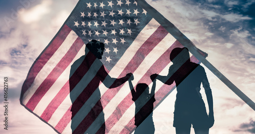 Patriotic man, woman, and child waving American flags in the air.