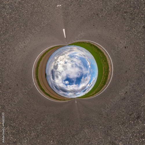 Inversion of blue little planet transformation of spherical panorama 360 degrees. Spherical abstract aerial view on road with awesome beautiful clouds. Curvature of space.