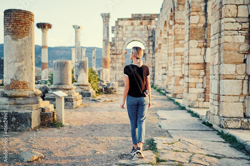 Happy young woman walking on ancient antique city Volubilis. Traveling by Morocco.