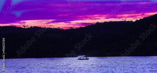 Boat, canoe, raft on the Huallaga River in the Peruvian high jungle. River among vegetation with light blue sky and white clouds.