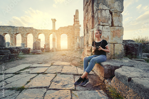 Tourism and hobby. Happy young woman taking photo of ancient antique city Volubilis. Traveling by Morocco. photo