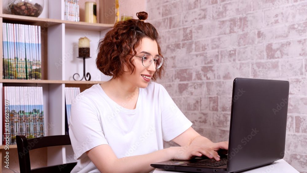 a woman with glasses works at home in a cozy environment remotely at a computer a woman with glasses works at home in a cozy environment remotely at a computer