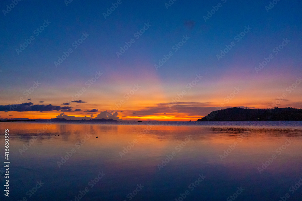 Wonderful sunset landscape on the seashore, colors of the sunset sky and silhouette of island in the water. incredible tropical sunset