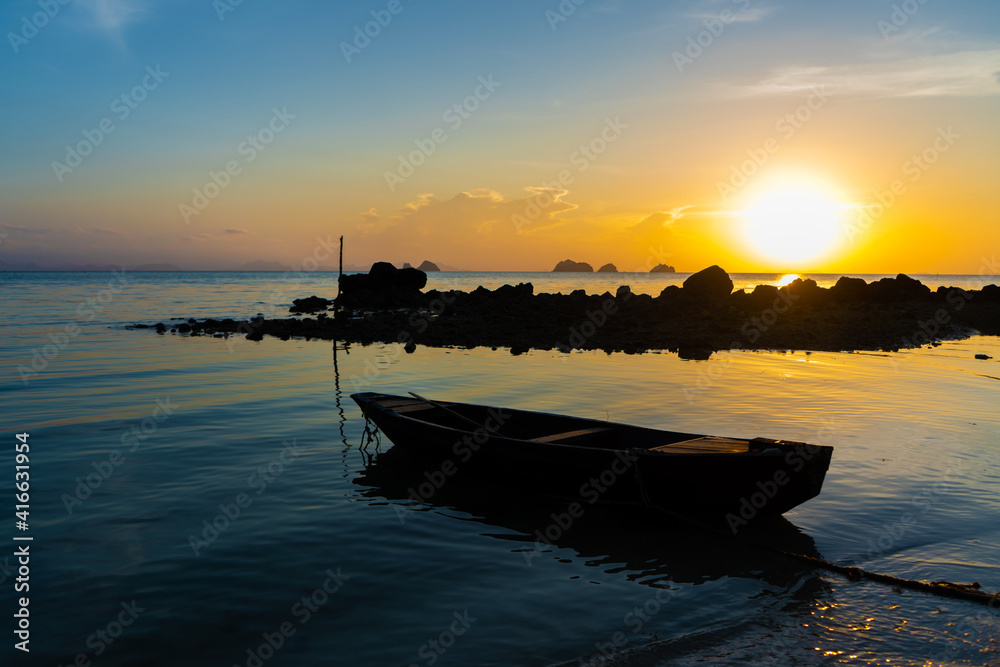 Beautiful sunset on the coast of a tropical island in Thailand, a silhouette of a boat in the ocean