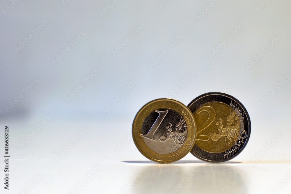 1 and 2 euro close up on neutral blurred background with place for text