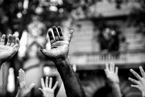 Multicultural hands raised in the air asking for freedom in a demonstration on street in black and white. Open palm of a black hand and white hands. Stop racism. Stop repression. photo