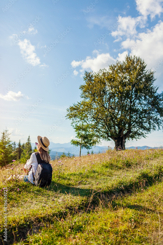 Traveling in summer Ukraine. Trip to Carpathian mountains. Happy woman tourist hiker sitting in flowers Traveling in summer Ukraine. Trip to Carpathian mountains. Happy woman tourist hiker sitting in flowers