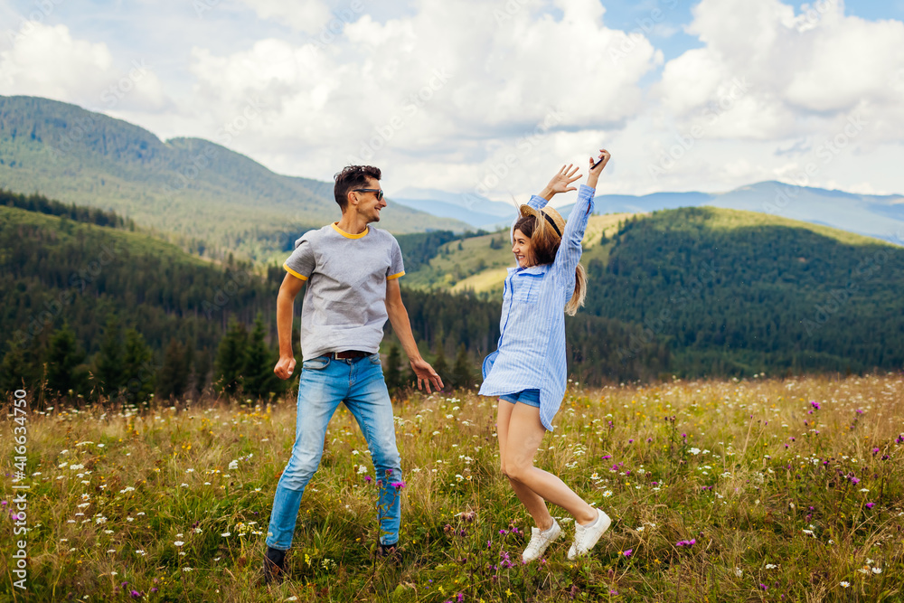 Young loving couple of tourists jumps feeling happy in Carpathian mountains enjoying view. Travelers have fun.
