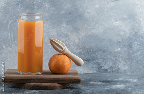 Fresh juice and orange with reamer on wooden board