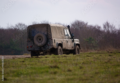 british army land rover defender 4x4 speeds along a dusty dirt track 