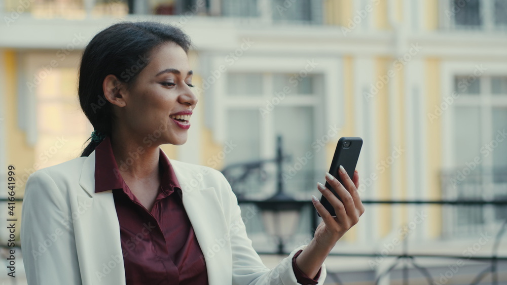 Smiling businesswoman having video chat outside. Lady looking phone screen