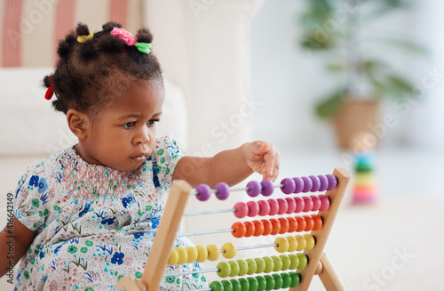 cute african american baby girl playing colorful abacus toy at home photo
