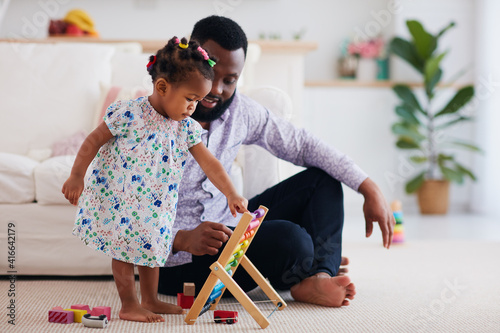 africam american family, father and daughter playing with wooden abacus and toys at home photo