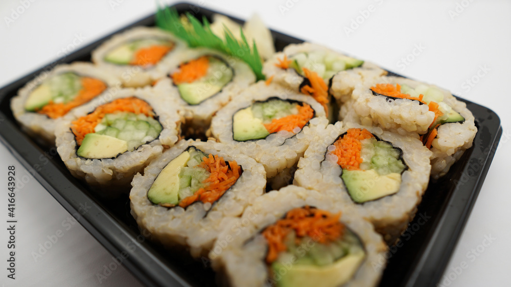 Takeout tray of vegetable sushi made with avocado, carrots, cucumber, and brown rice. Takeout tray of vegetable sushi made with avocado, carrots, cucumber, and brown rice.
