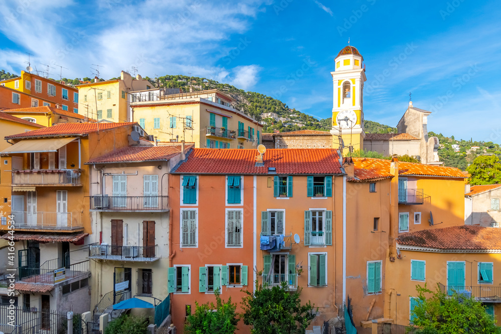 Colorful village of Villefranche-Sur-Mer, France and the yellow church clock tower of Saint Michel Church in the seaside town on the French Riviera.