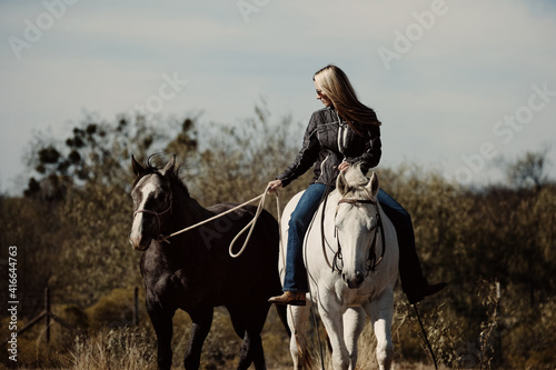 Western lifestyle with woman riding horse bareback while ponying through Texas field.