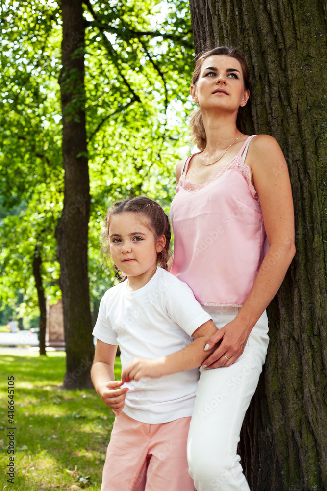 © iordani - young pretty mother walking with little cute daughter outside in green park, lifestyle poeple concept