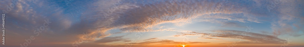 intense dramatic panoramic sunset with cirrus clouds illuminated by golden rays of the sun