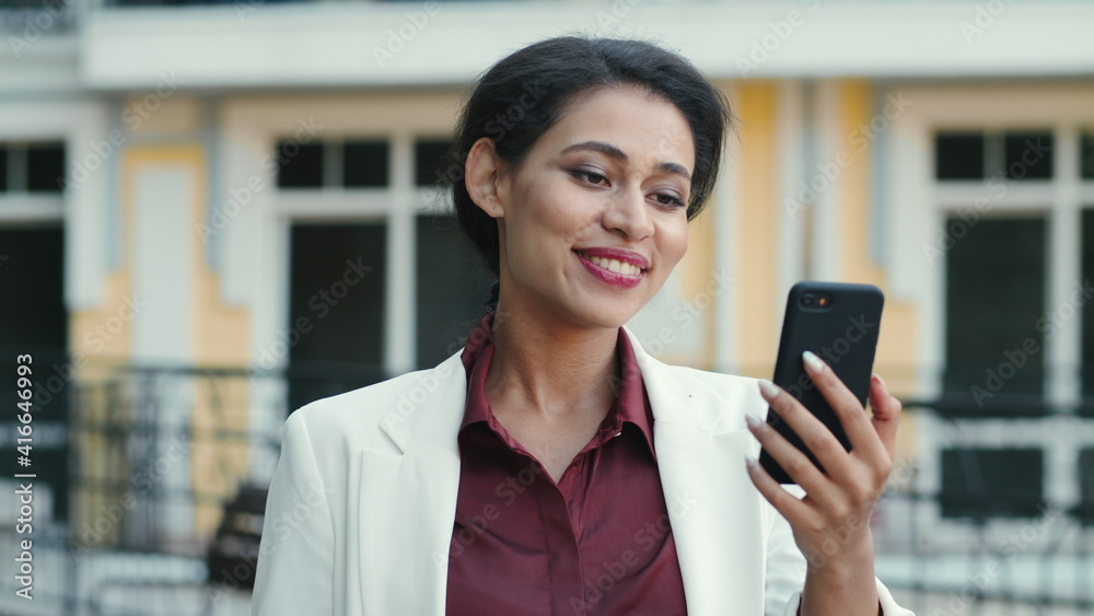 Smiling mixed race woman video chatting outside. Lady looking phone screen Smiling mixed race woman video chatting outside. Lady looking phone screen