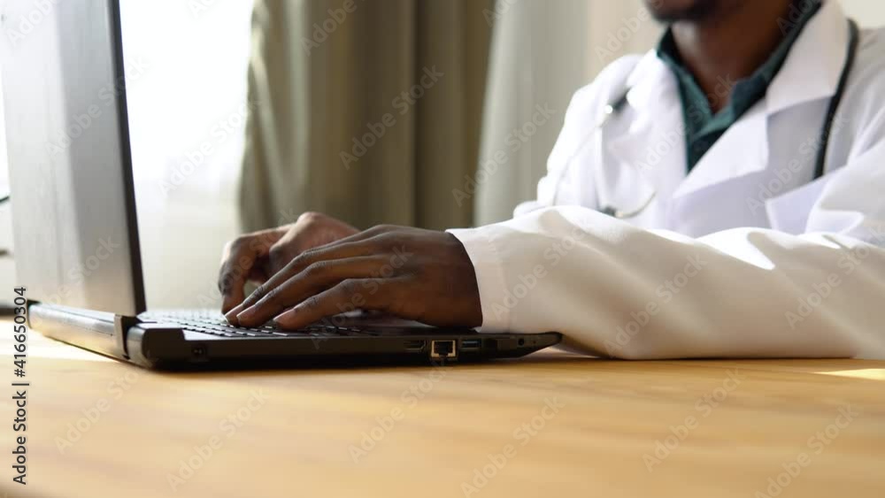 Close up of hands of african american male doctor working on laptop in clinic Close up of hands of african american male doctor working on laptop in clinic