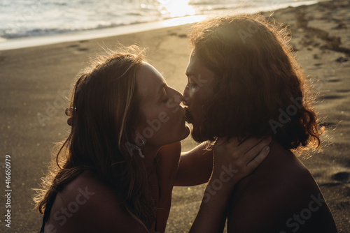 close-up. On the beach sand against the ocean background a girl kisses on the lips of a man. High quality photo