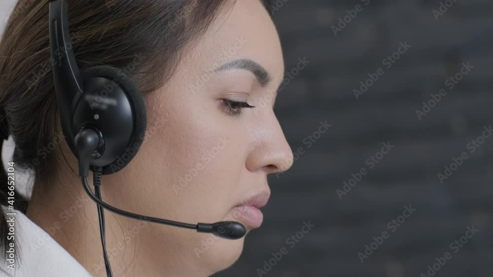 Woman call centre operator, customer support agent wears headset consults client online, typing on laptop, talk in internet computer chat, helpline operator secretary make conference video call