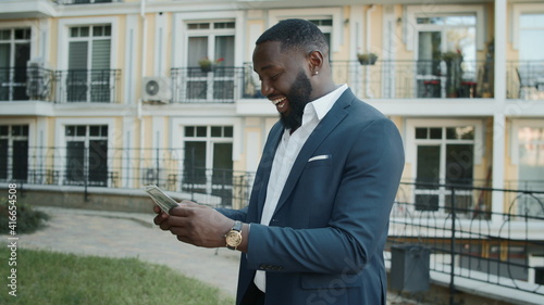 African businessman holding cash outside. Cheerful man counting money outdoors