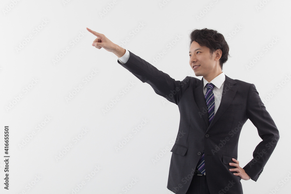 A young Asian business man is pointing with smile A young Asian business man is pointing with smile
