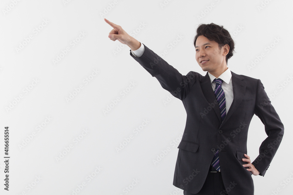 A young Asian business man is pointing with smile A young Asian business man is pointing with smile