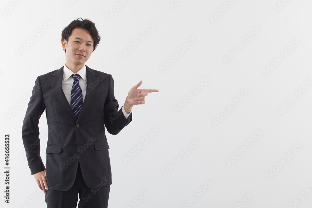 A young Asian business man is pointing with smile A young Asian business man is pointing with smile