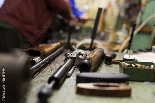 Disassembled shotgun parts and cleaning kit on the wooden table. High quality photo © JackF