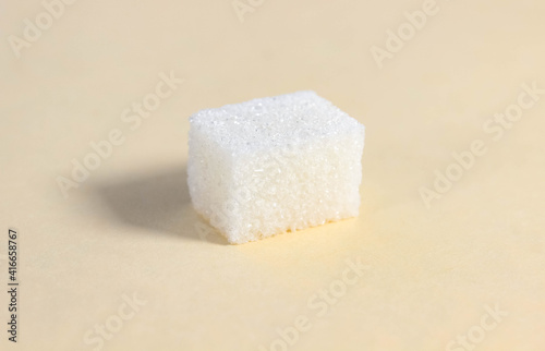 One rectangular sugar cube on a beige background.