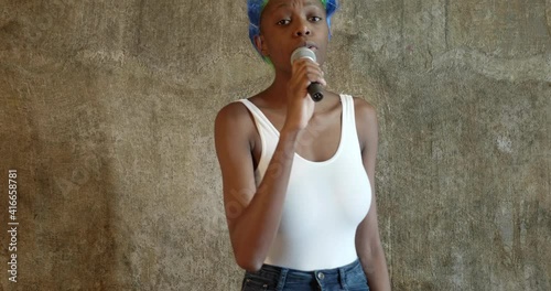 glamor, expressive, females, funky, performing, singer, African american woman in white bodysuit and jeans in bright multicolor punk wig sings karaoke with microphone in her hands