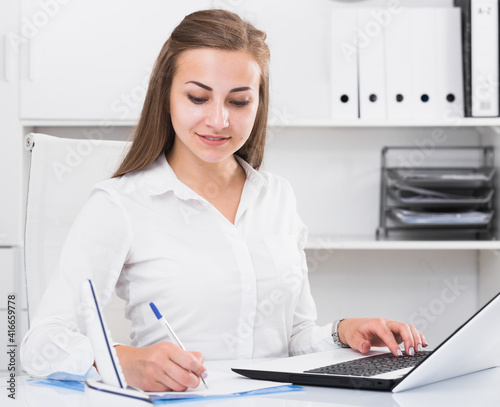 Young office worker is working with documents and laptop in the office.