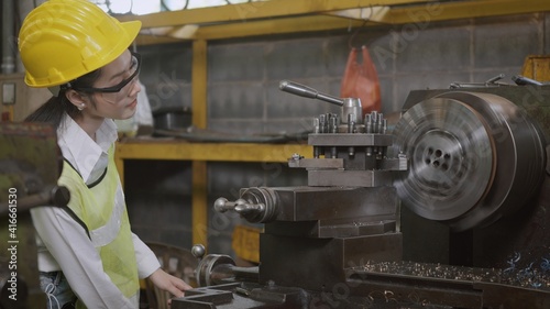 Asian professional mechanical engineer or operation woman wearing uniform goggles safety working on workshop metal lathe industrial manufacturing factory, Heavy industry lathe worker woman
