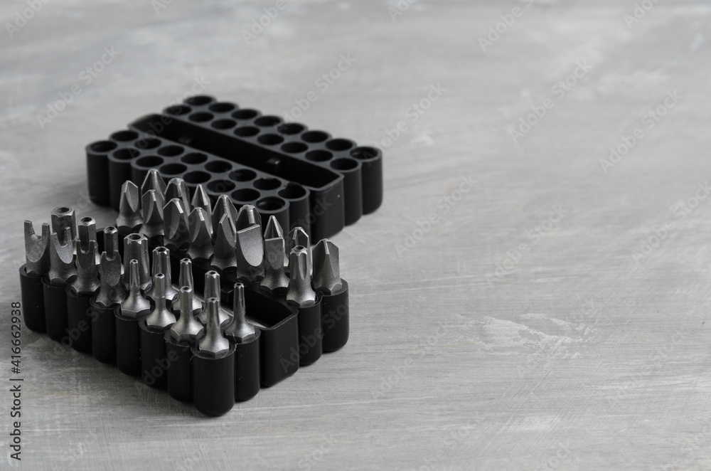 Screwdriver bits for various standards in a convenient package on a gray concrete background. Screwdriver bits for various standards in a convenient package on a gray concrete background.