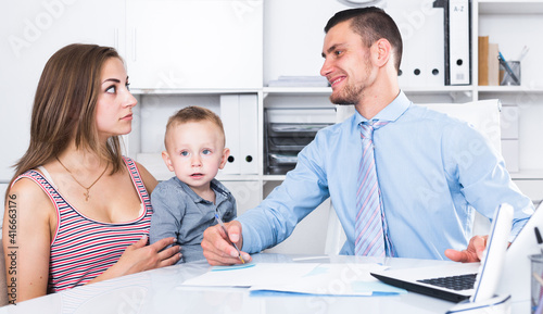 mother and little boy andadvising with adult banker worker in modern office